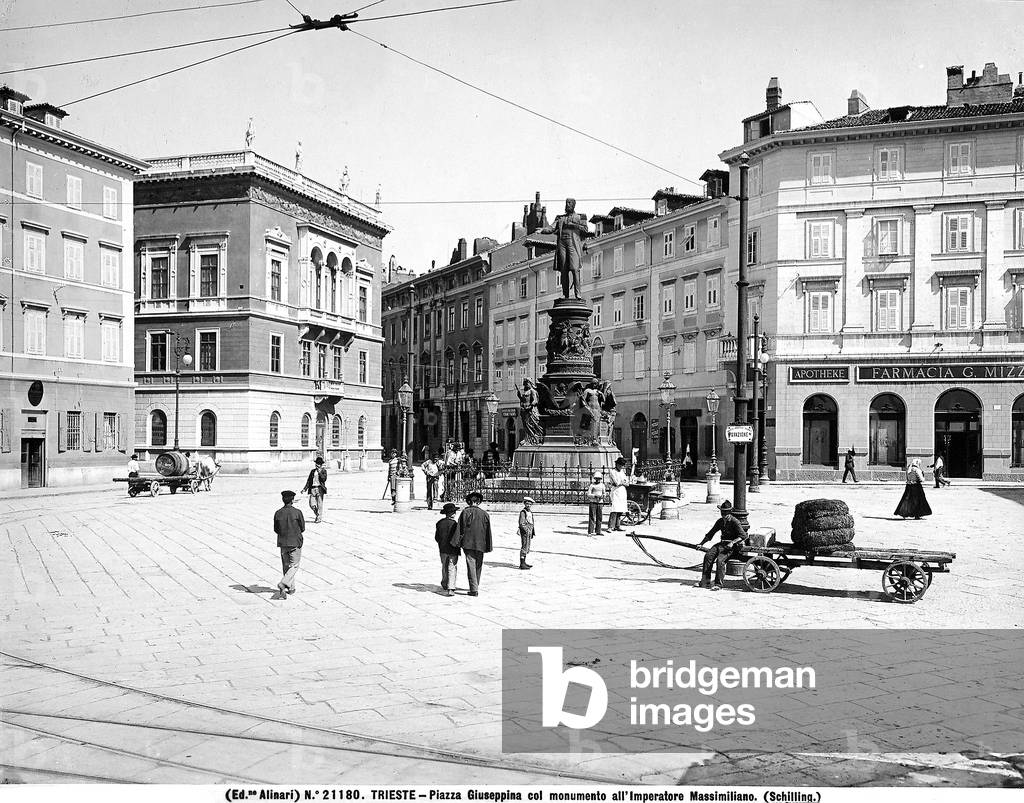 View of Piazza Venezia, formerly Piazza San Giuseppe in Trieste, with the statue of Emperor Maximillian in the center, work by Johannes Schilling. The square is full of passersby.