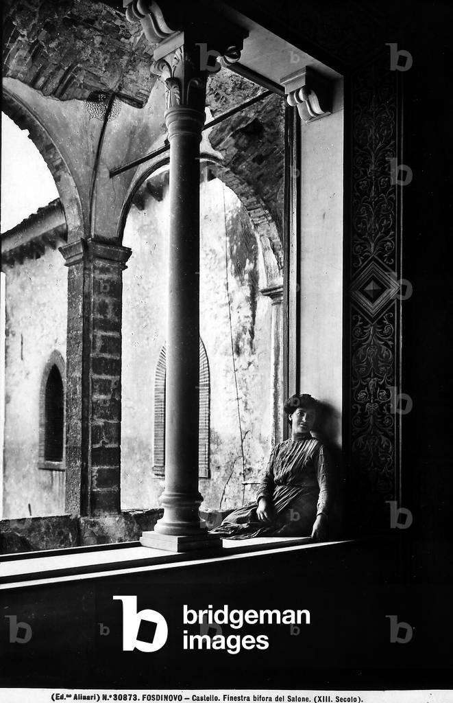 View of woman sitting on the sill of a window with two lights in the salon of the Castle of Fosd Castle, Fosdinovo
