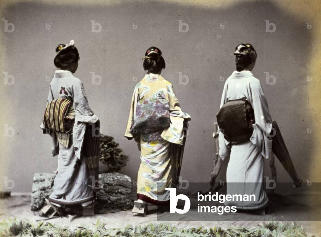 Three young Geishas pose from the rear, showing the large knot on their back formed by the characteristic 'Obi', the elegant band of silk wrapped around a kimono (coloured photo)