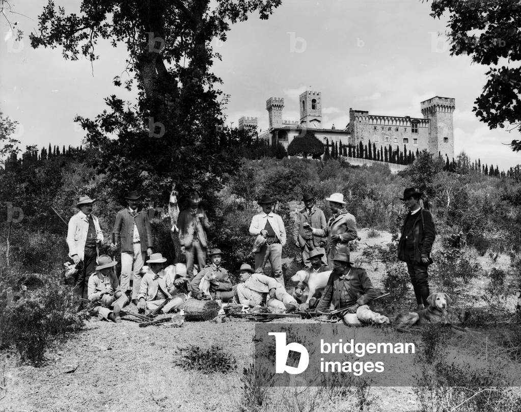 Portrait of a group of hunters in everyday dress, with guns and dogs. Some are drinking wine. In the background, Badia of Passignano