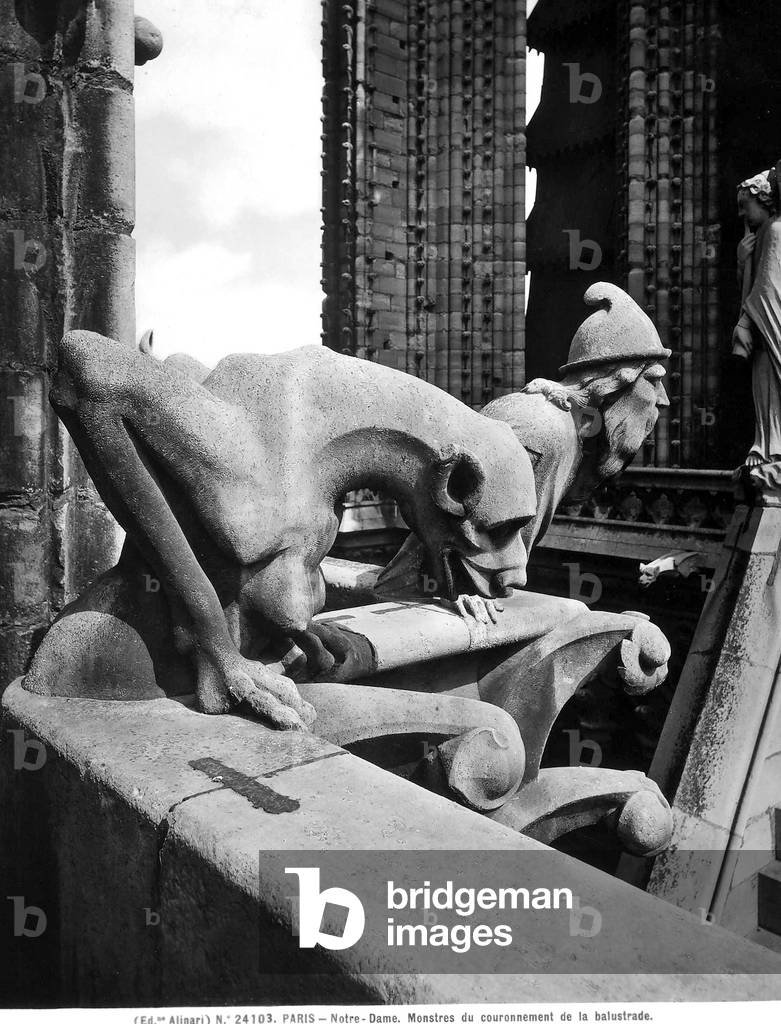 Statues depicting a monstrous figure and a man with a beard and hat looking over a balustrade. Detail of the sculptures located on a terrace in the Cathedral of Notre-Dame, Paris