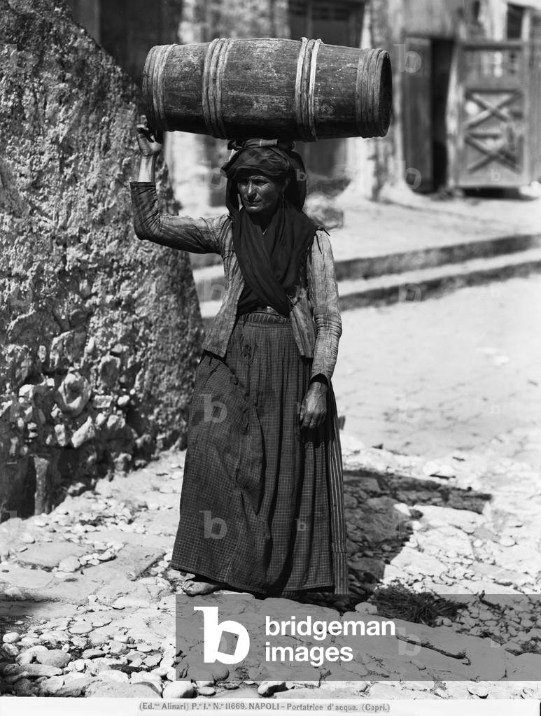 Elderly woman carrying a barrel of water on her head, standing on a staircase in Capri, near Naples, Campania