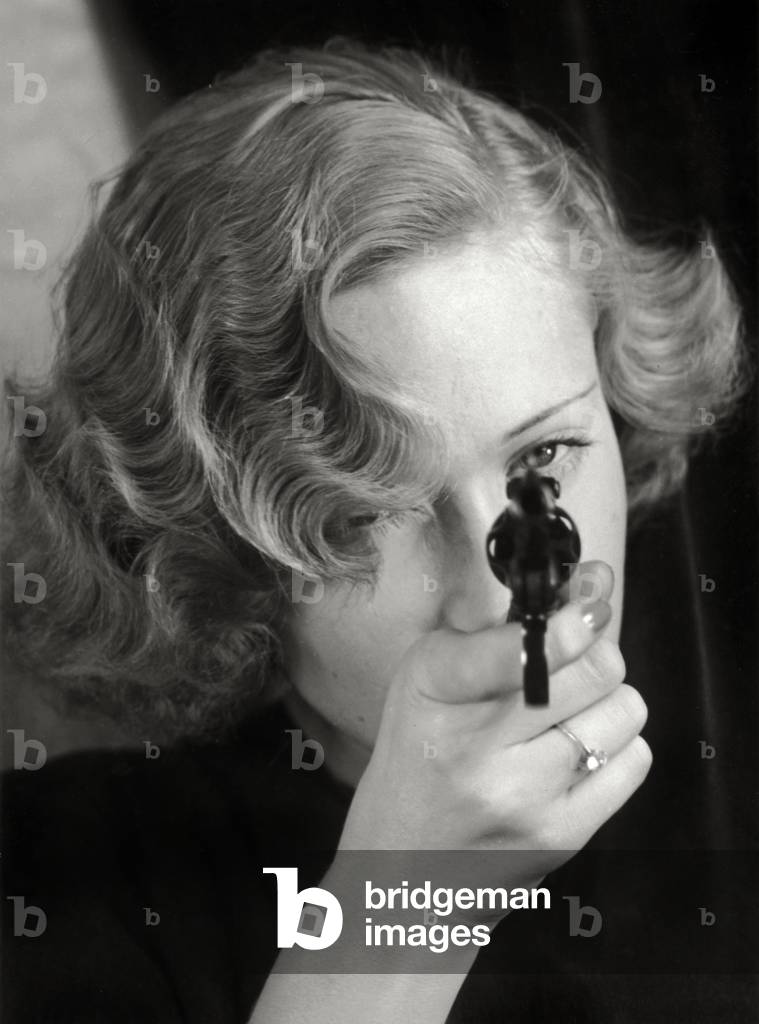 Portrait of a young woman pointing a gun