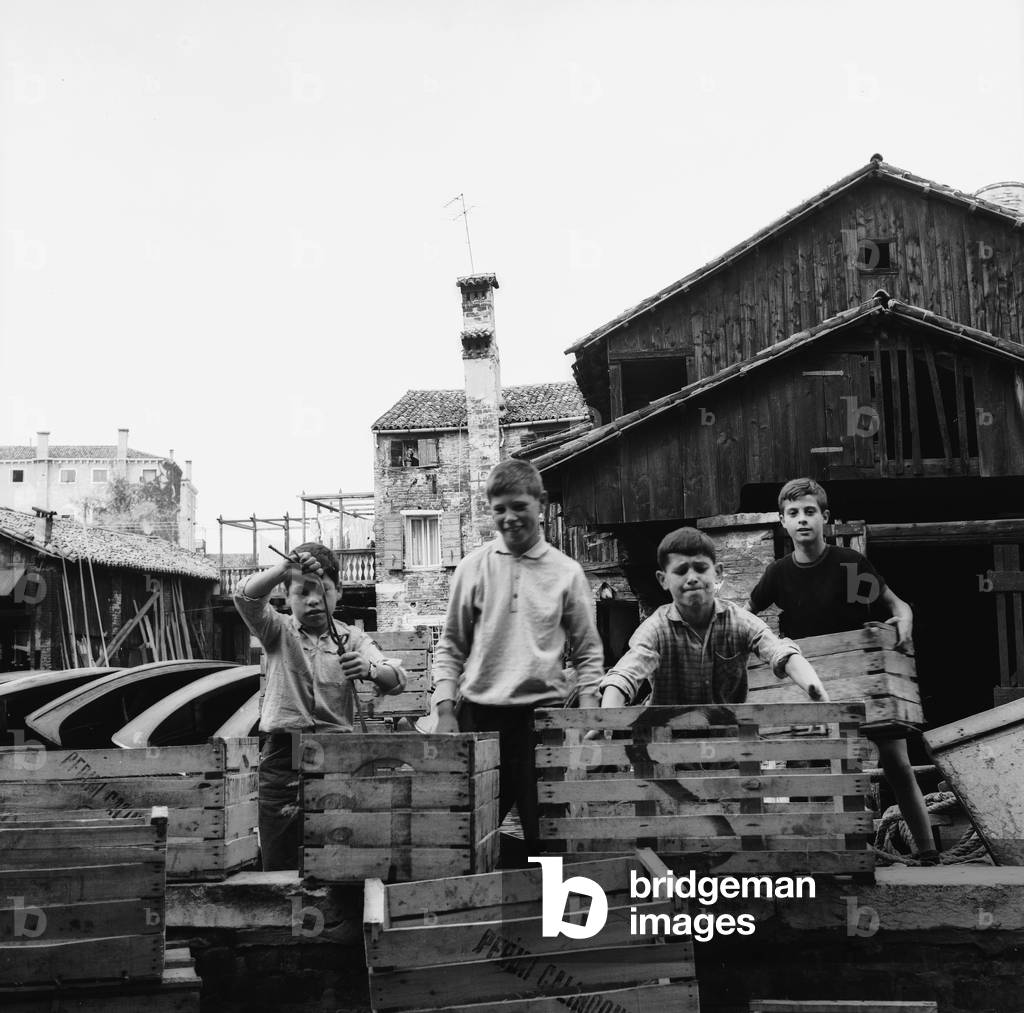 Group of children raised boxes in a shipyard in Venice (b/w photo)