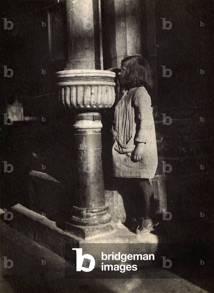 Portrait of a little girl next to a holy water font
