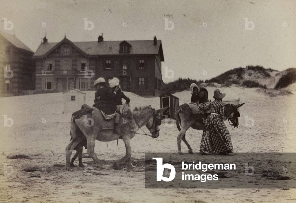 Children riding a donkey on the beach of Berck near Calais