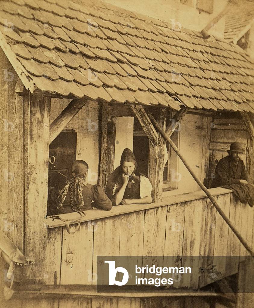 Two young women and a man looking out a balcony in a house in a village of Freiberg, Germany,  1880 (print on double-weight paper)