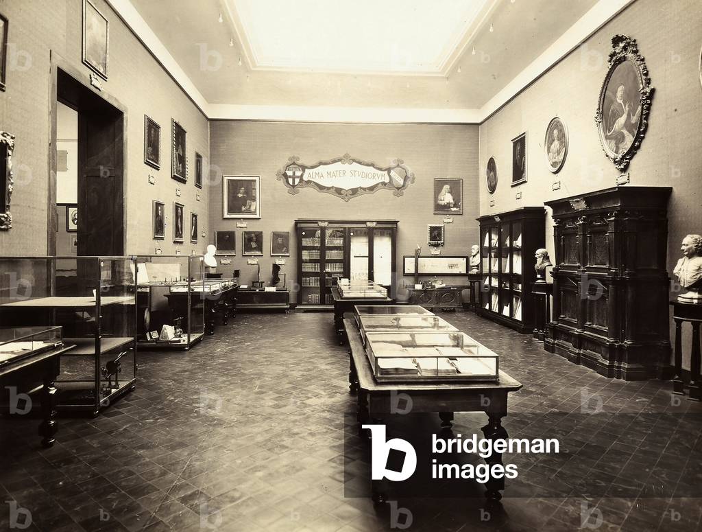 View of a room at the university of Bologna. in the back on the left, the appliance of the scientist Augusto Righi. On the right the appliance of the astronomer Gian Domenico Cassini. In the glass showcase are preserved objects of various kinds. On the wall are some paintings and a painted motto, ALMA MATER STUDIOREM. The picture was taken during the Exhibition of Science History in 1929, in Florence.