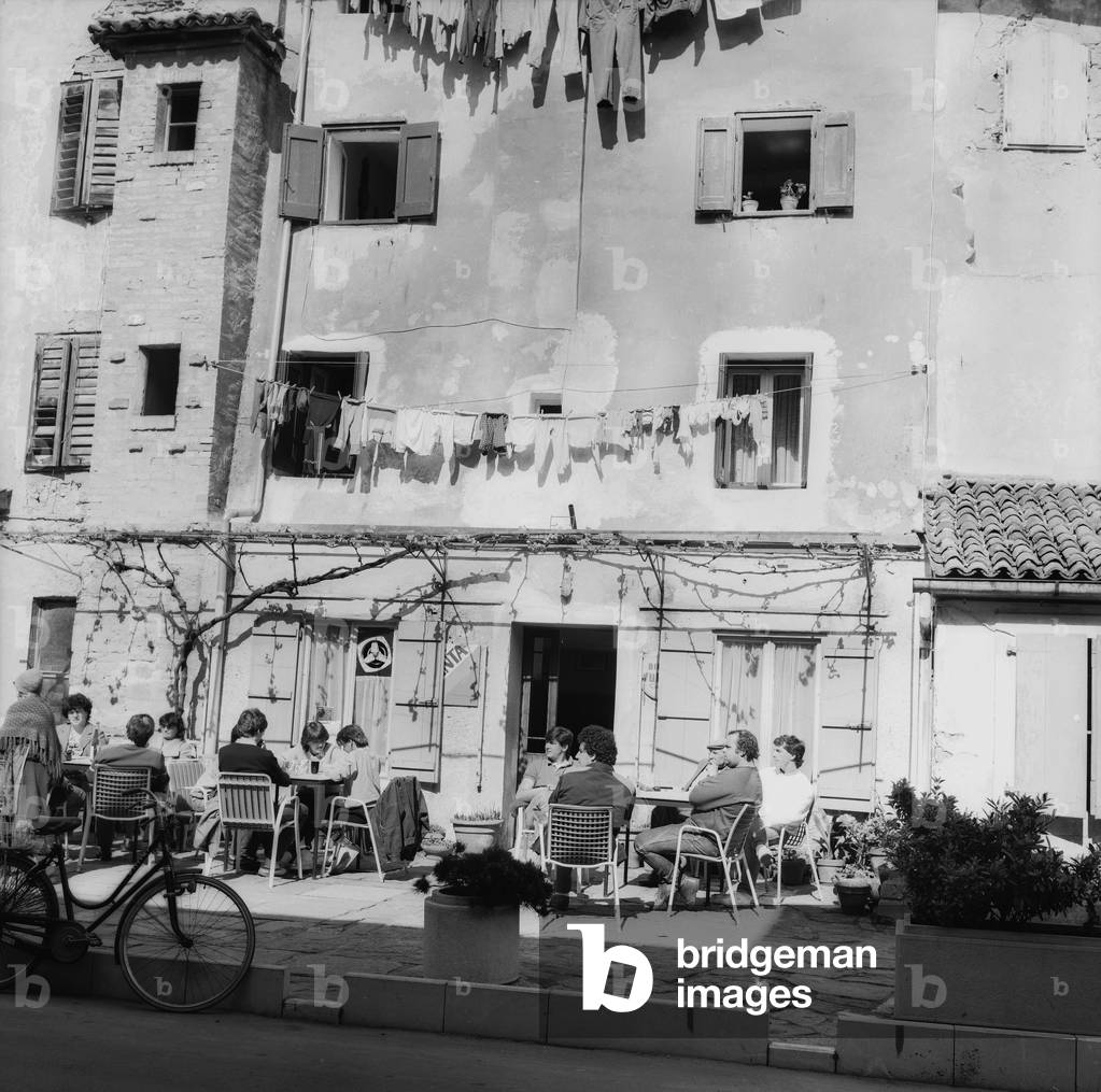 Customers at an outdoor cafe in the old town of Grado (b/w photo)