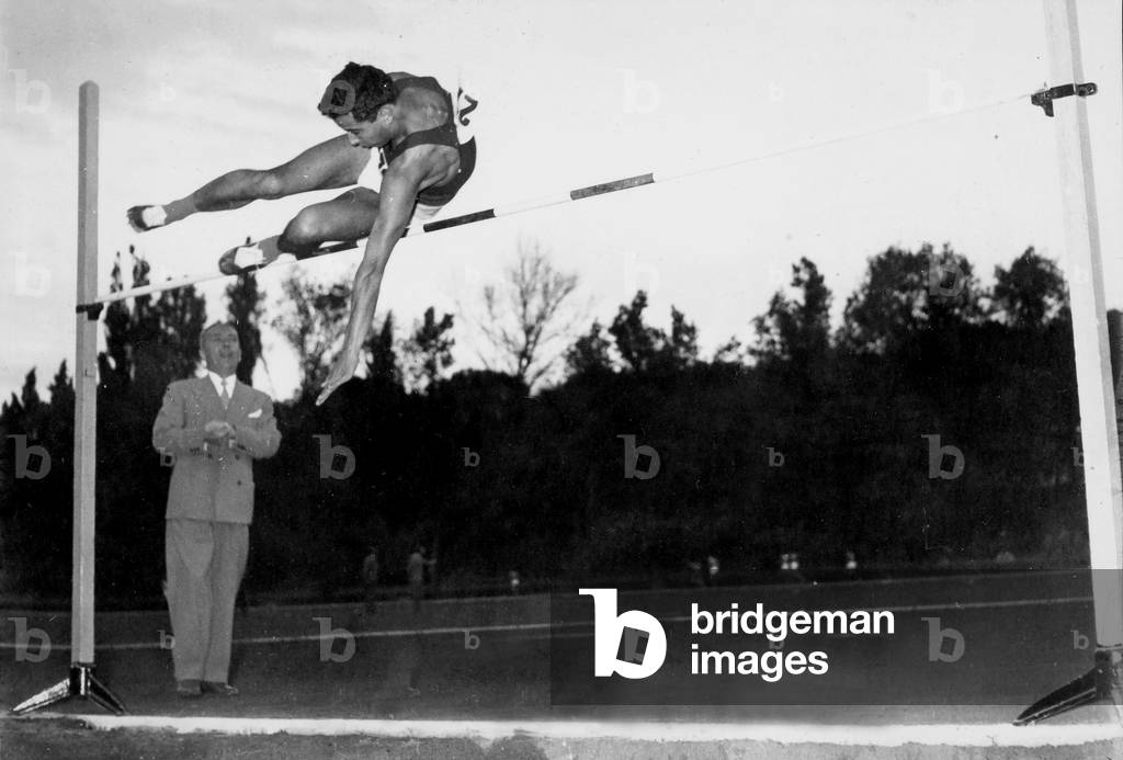The ceremonies and games called by the Centro Sportivo Italiano: an athlete doing the high jump before the judge of the competition