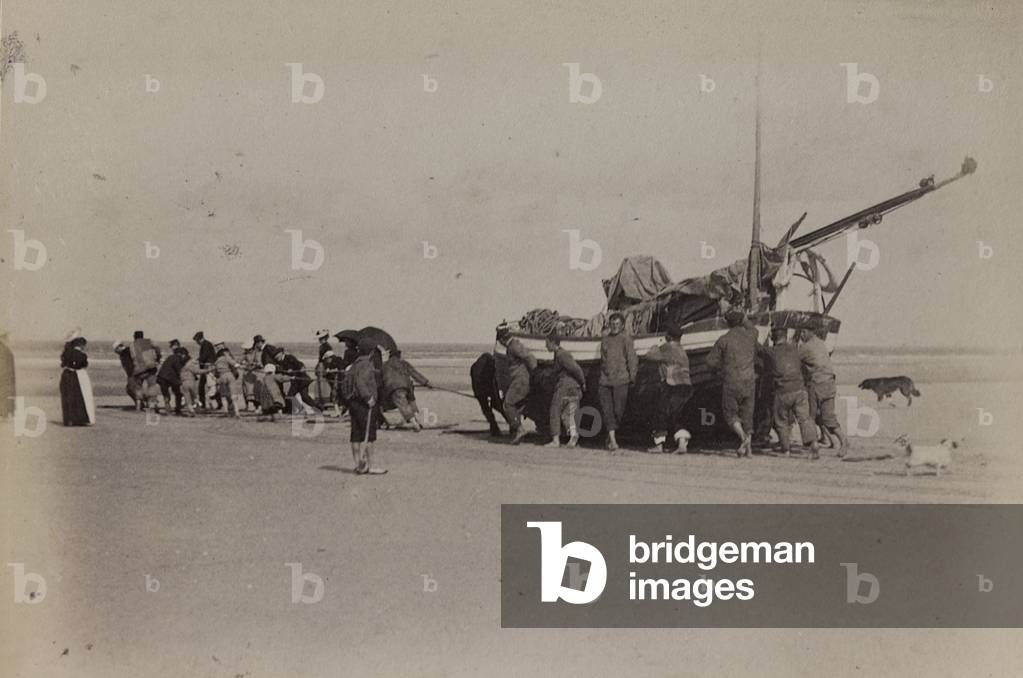 Group of people drag a boat on the beach of Berck near Calais