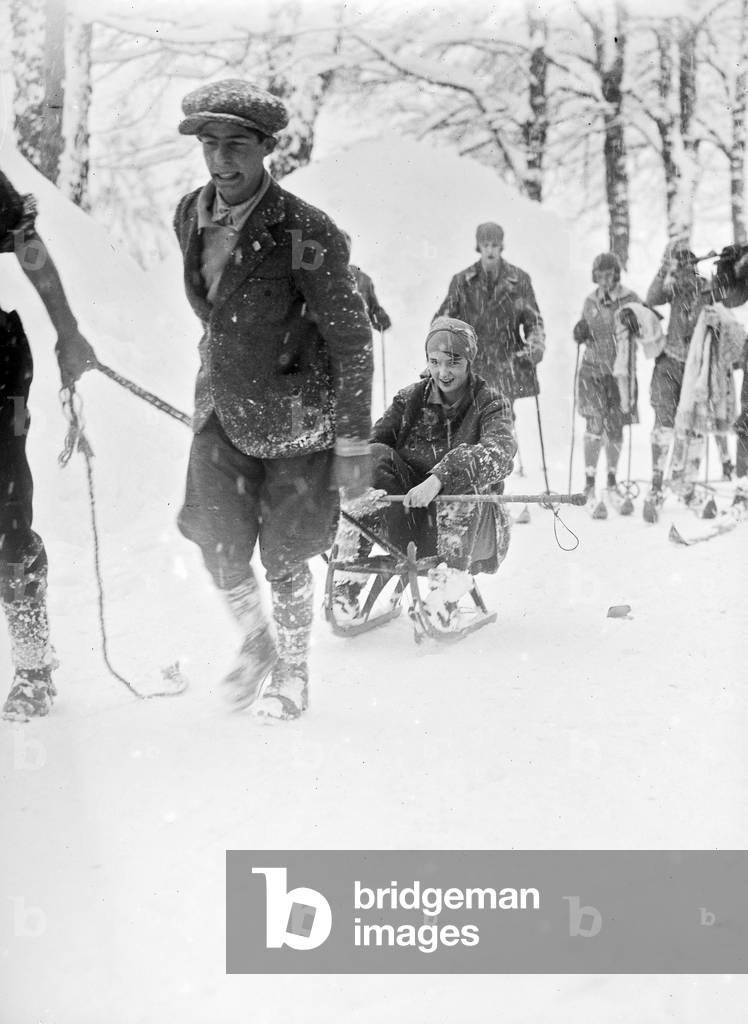 Girl on a sled during a snowfall in Abetone