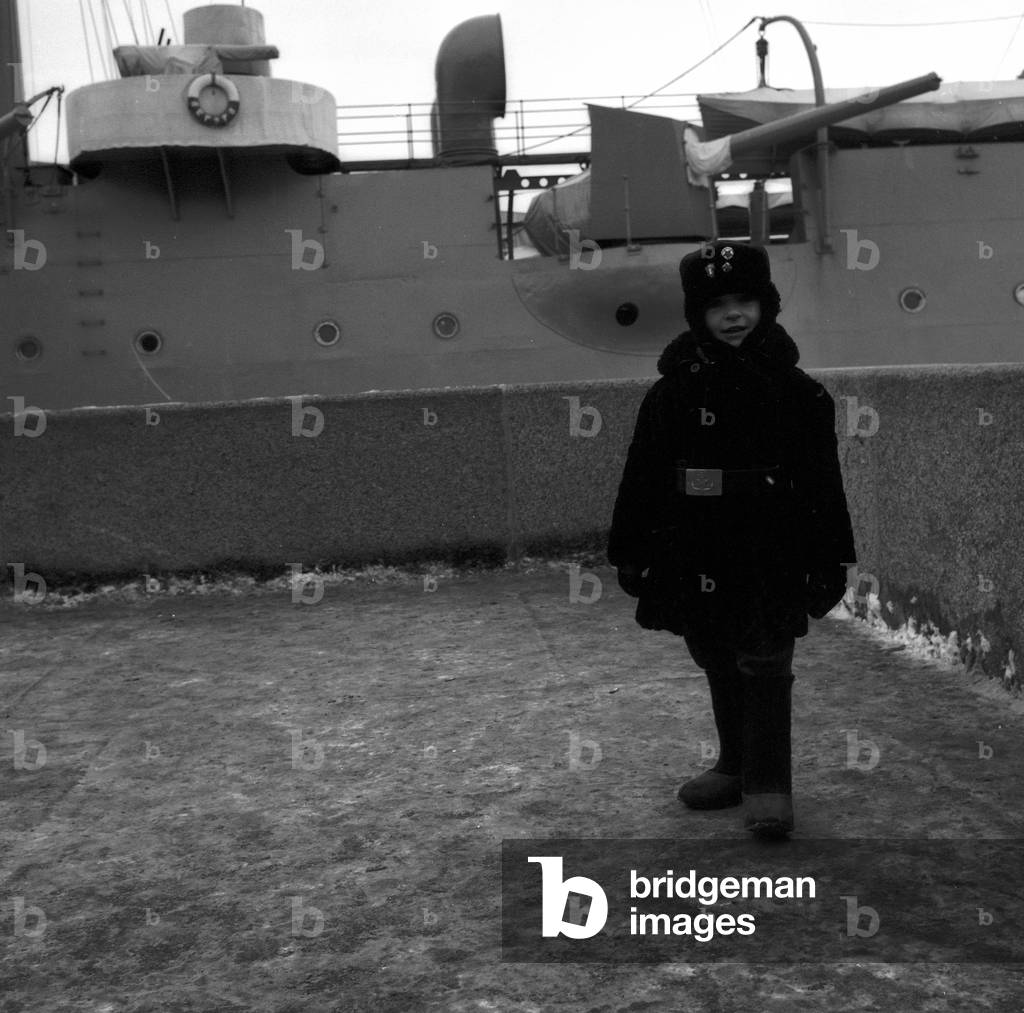 Baby photographed in front of a military ship in St. Petersburg (b/w photo)