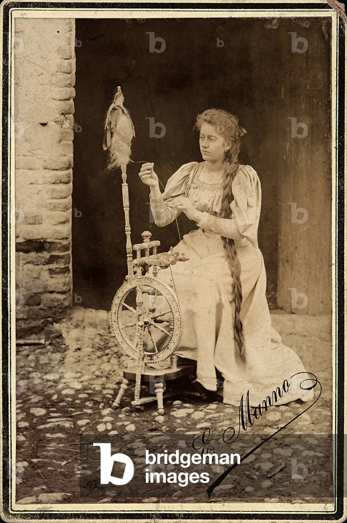 Portrait of a young woman spinning wool