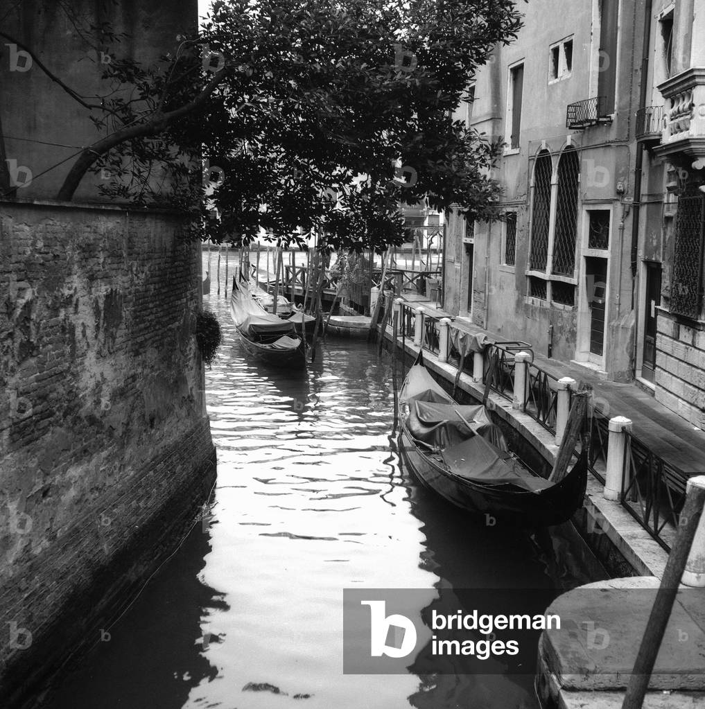 Gondolas in a canal in Venice (b/w photo)