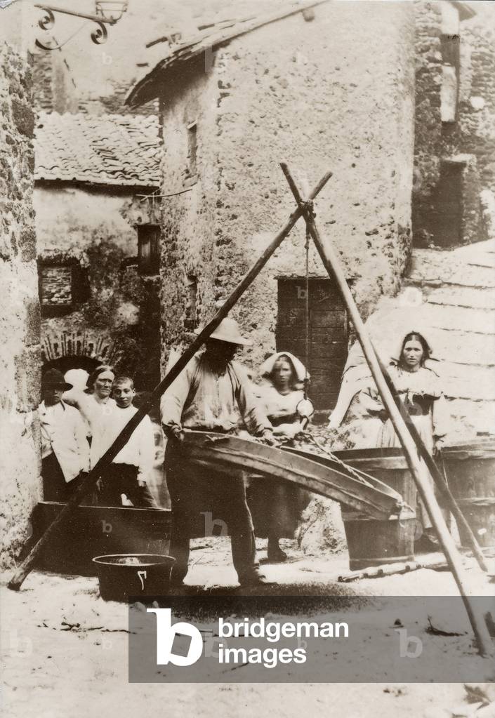 Farmer at work with a sieve; behind him a few women and children.