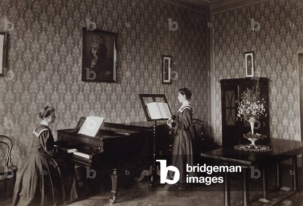 Young woman playing a piano accompanied by another singing youth in a religious institution