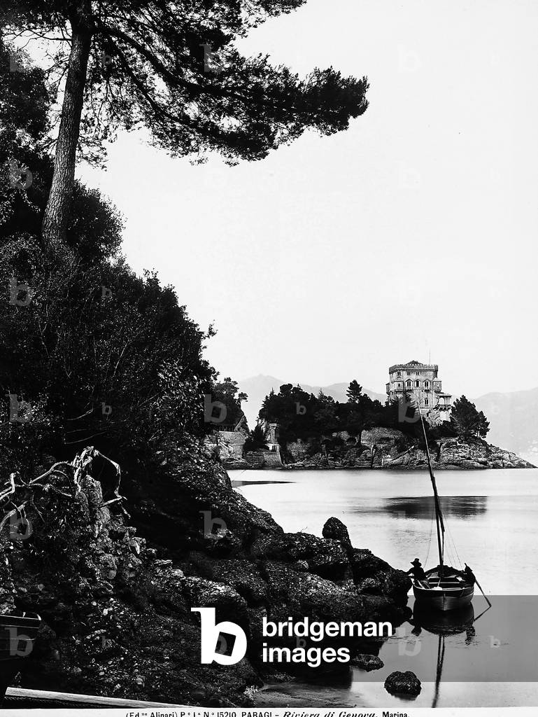 The inlet of Paraggi, locality near Santa Margherita Ligure, with a moored boat near a rock. A small town on the sea is visible in the background.