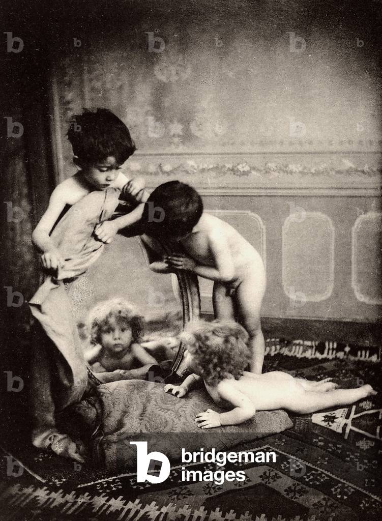 Three small children, nude, play with a mirror