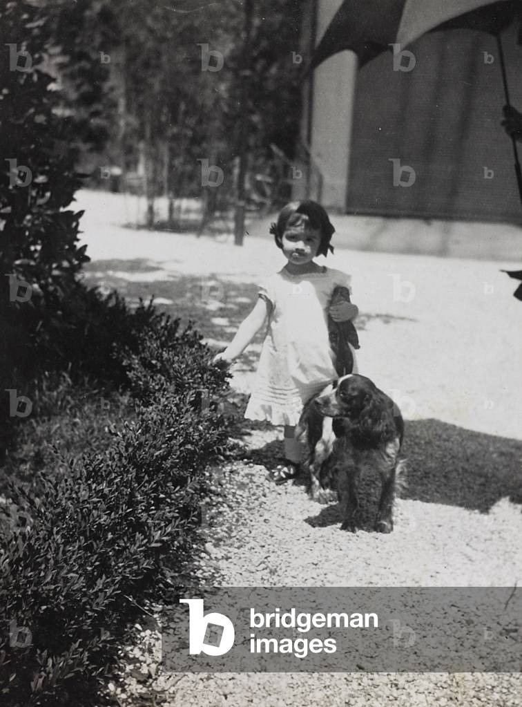A little girl with a dog in a garden; the support contains the indication 