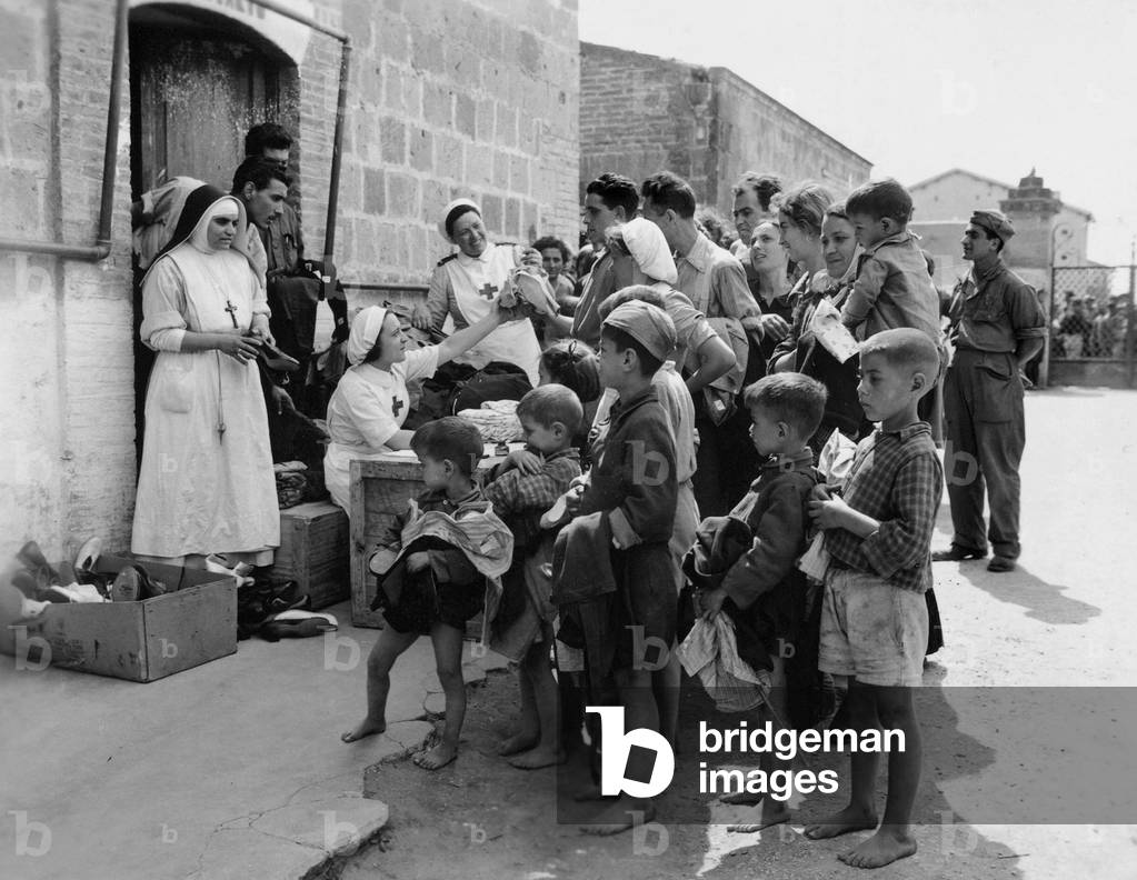 Nuns and volunteers from the Italian Red Cross distributing clothes at an aid center for war refugees in Fondi, Italy