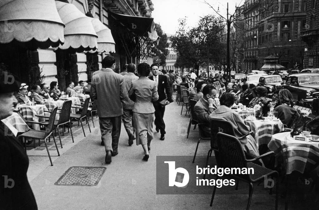 A couple strolls with others near an outdoor cafè on Via Veneto in Rome