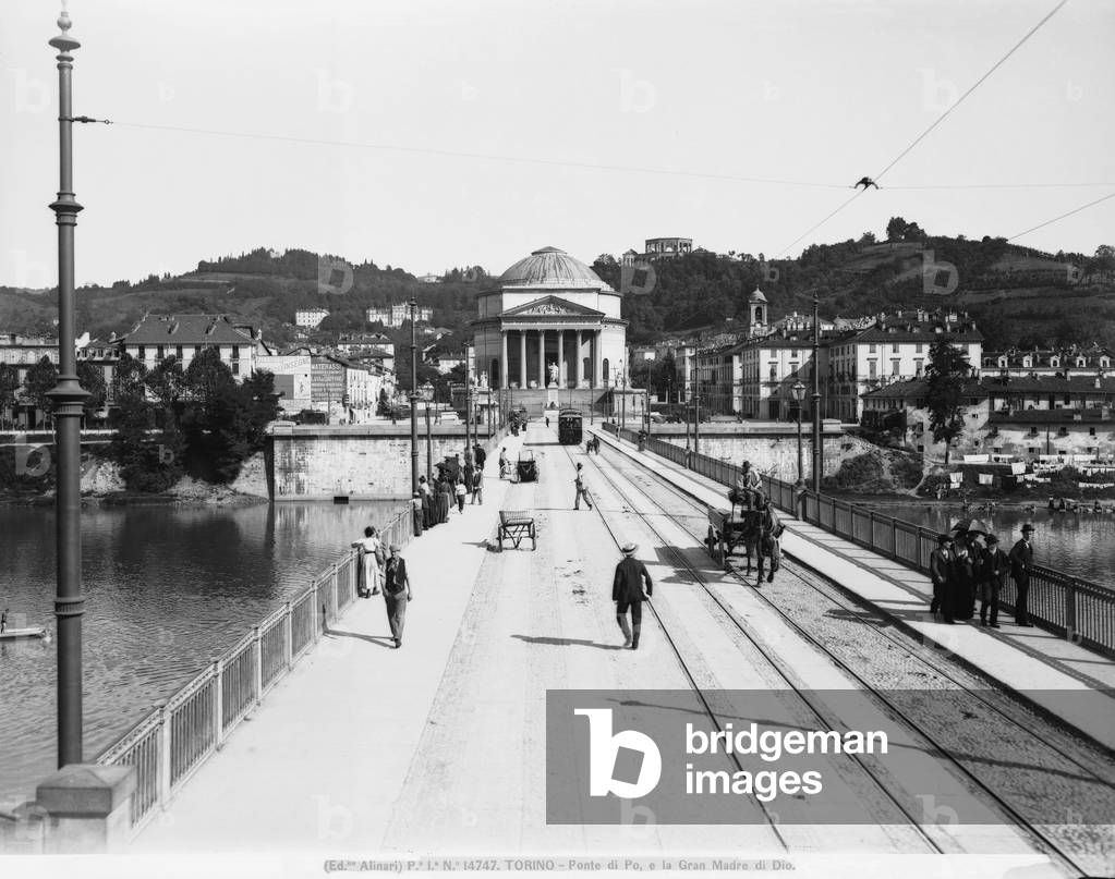 View of the Vittorio Emanuele I Bridge or of the Po River, in Turin. In the background the Gran Madre di Dio is visible. It is a neo-classic structure with hexastyle pronao and circular ceiling. Some passers-by and a horse carrying a cart are visible on the bridge