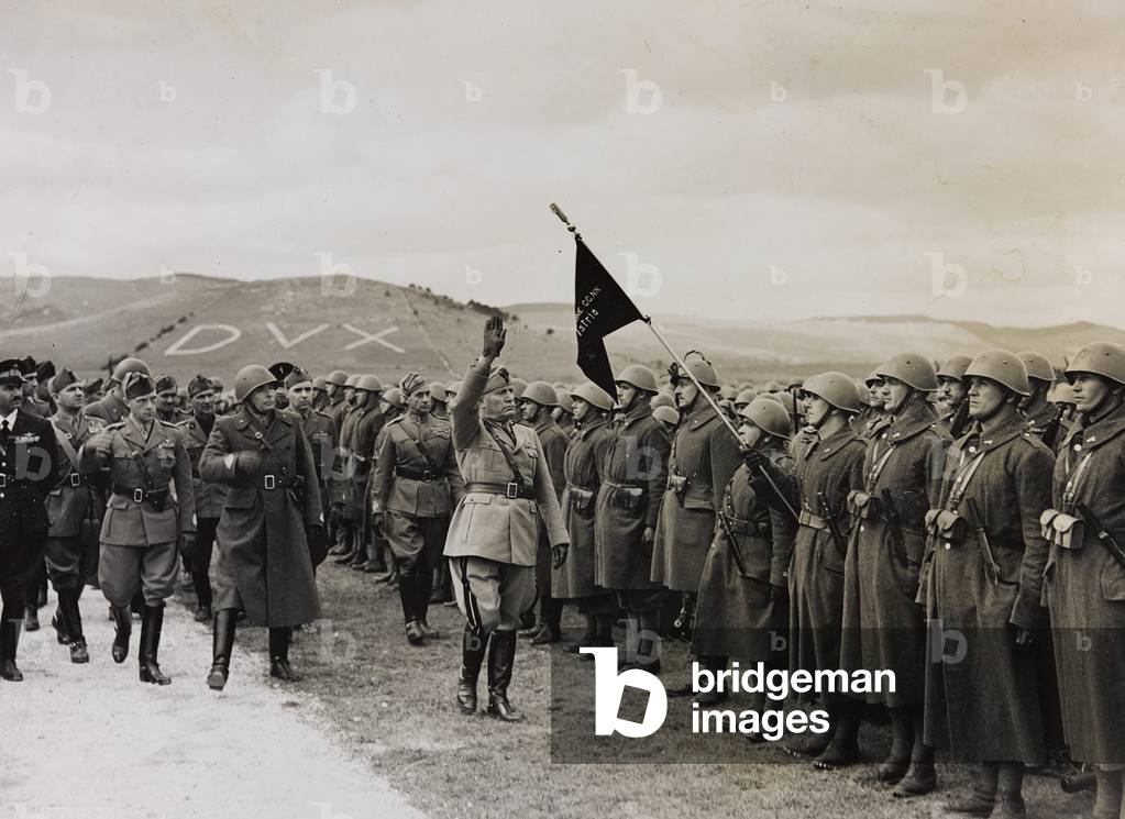 Benito Mussolini controls a department of the Militia of the framework of an Infantry Division; on the background the written Dux (b/w photo)