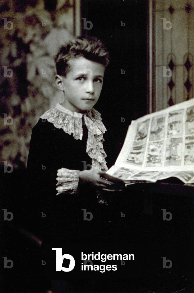 Half-length portrait of a boy leafing through a comic book
