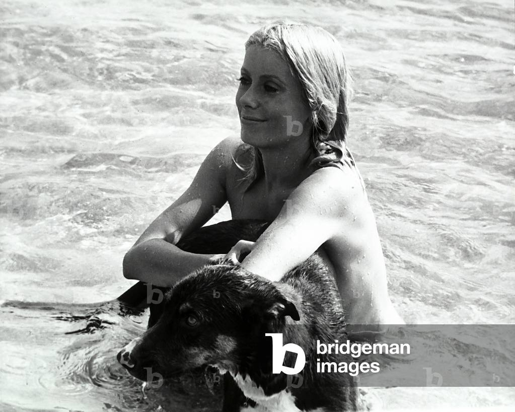 The French actress Catherine Deneuve bathing in the sea with her dog.