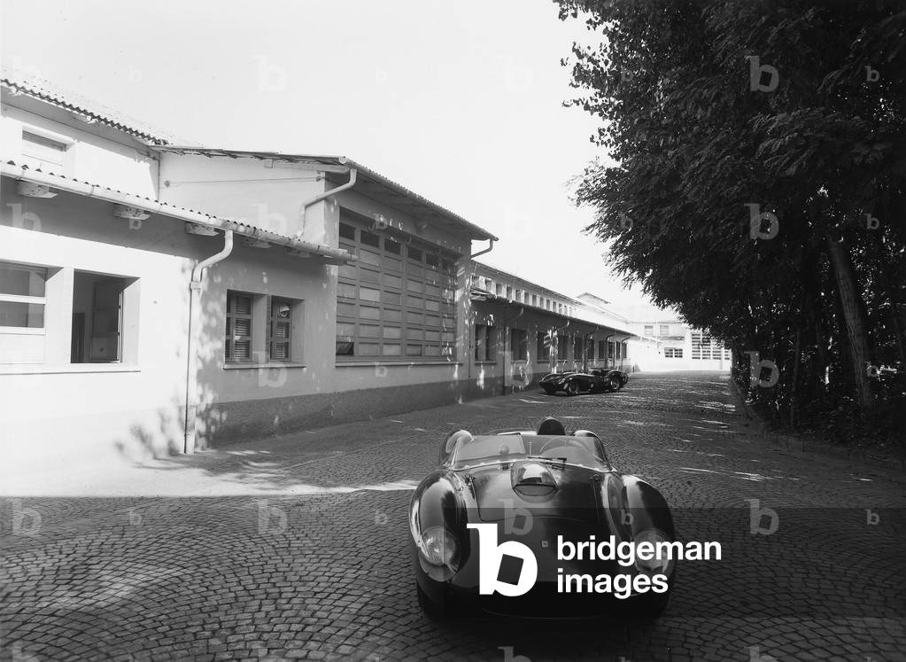 Outside view of a Ferrari factory. In the background and foreground are two sports cars produced by the company., 1950 - 1959 (photo)