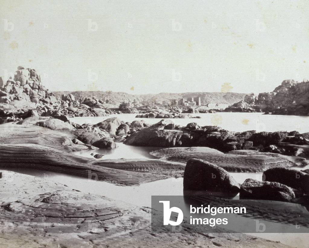 Panorama with ruins in upper Egypt. In the foreground the waters of the Nile running through a rocky landscape