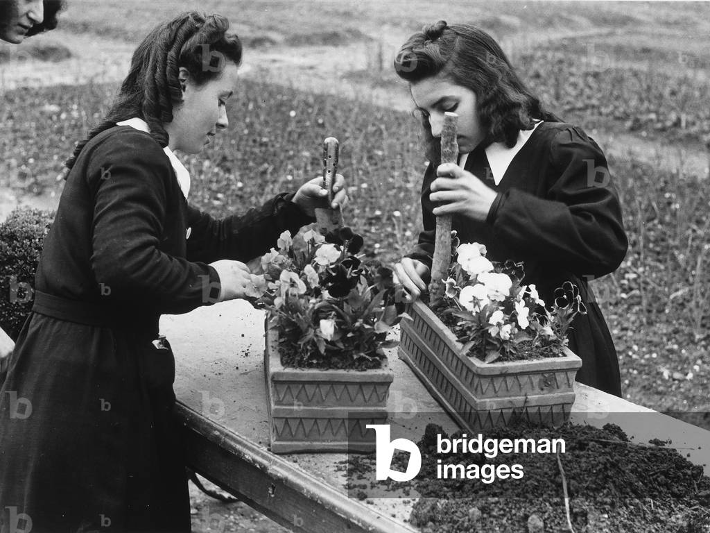 Two young women in a garden while gardening.