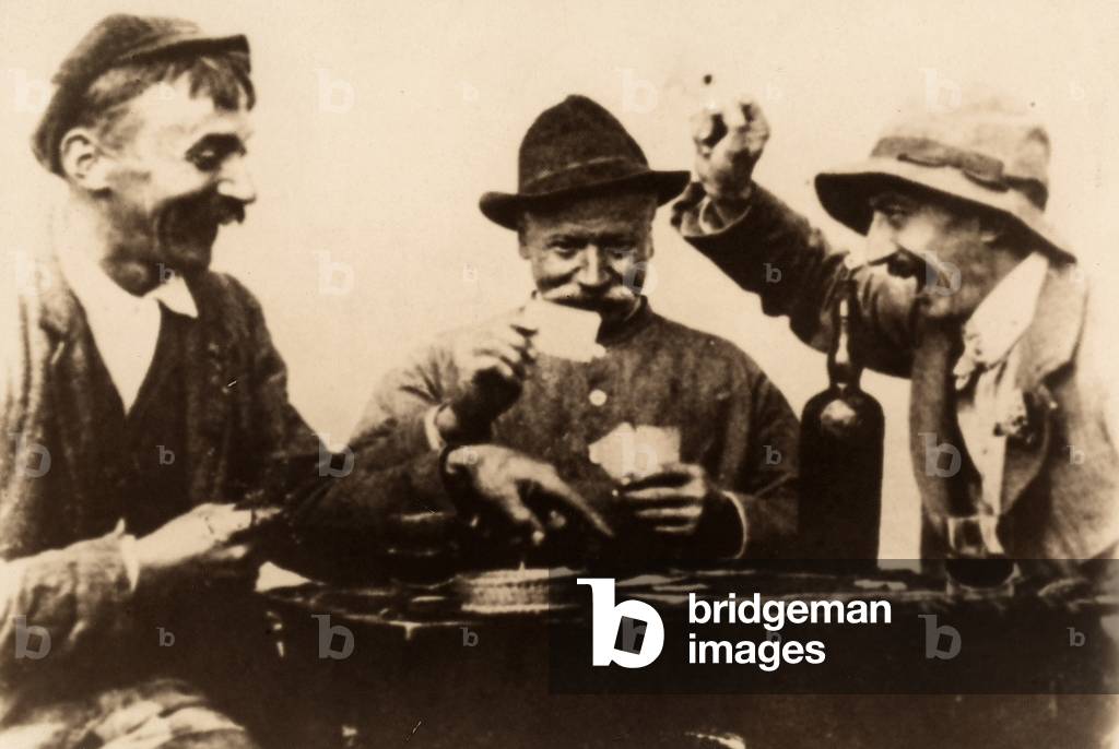 Three men seated at a table for a game of cards.