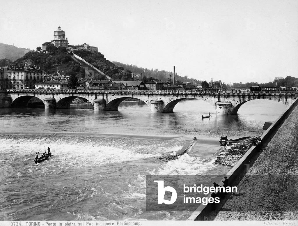 View of the Po river in Turin crossed by the Vittorio Emanuele I Bridge. In the background is the Mountain of the Capuchins with the Church of the Grand Madre di Dio on top.