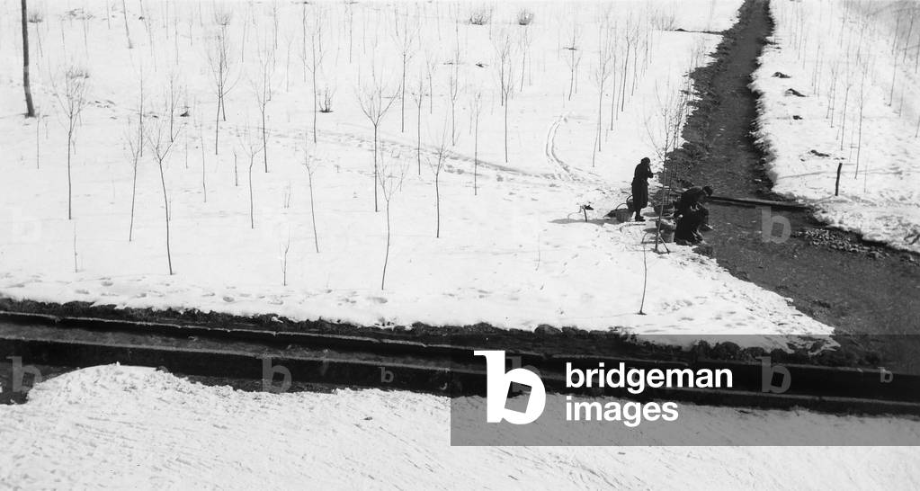 Snowy landscape with women on the banks of a river