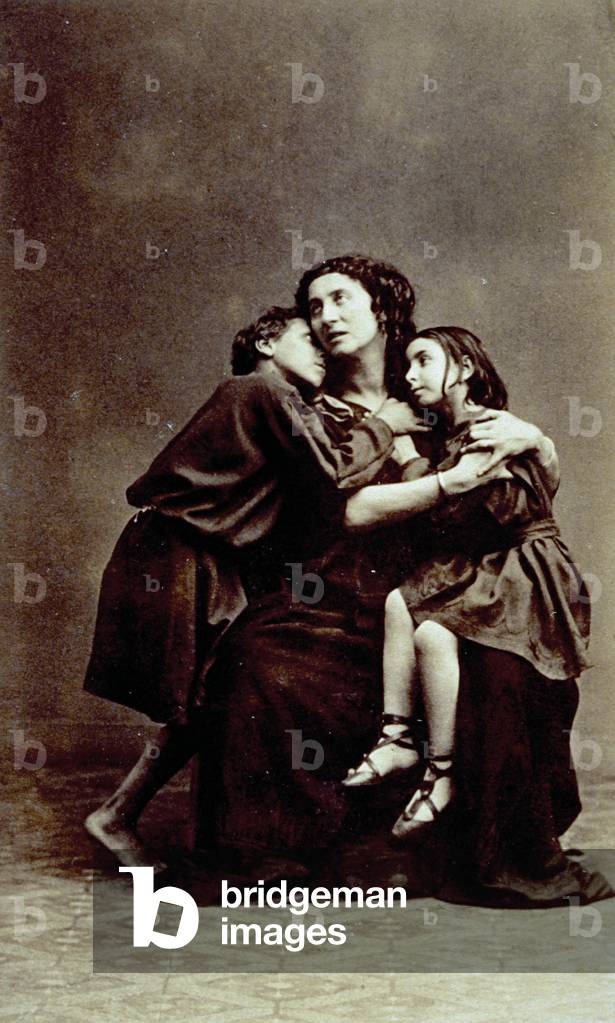 Studio portrait of Adelaide Ristori. She is wearing stage costume and is posing with two children
