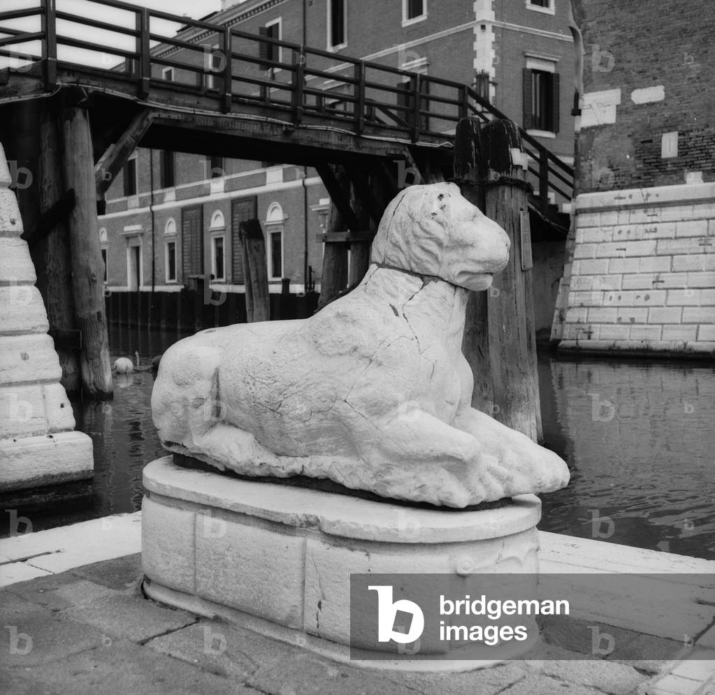 Lion carved in front of a canal in Venice (b/w photo)