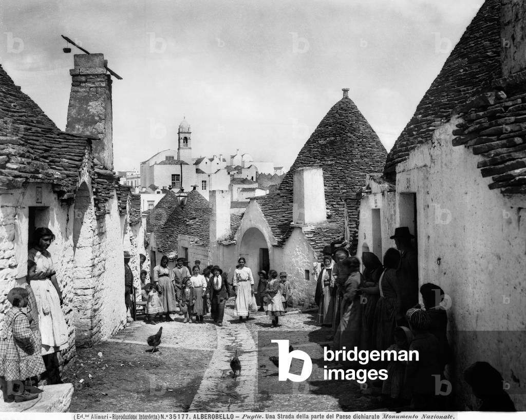 View of a busy street with cylindrical houses with conical roofs, Alberobello. 