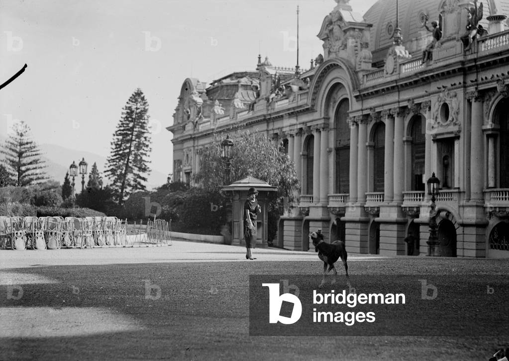 Portrait of a woman with a dog; in the background the theater of the Casino, Monte Carlo, 28/09/1924 (b/w photo)