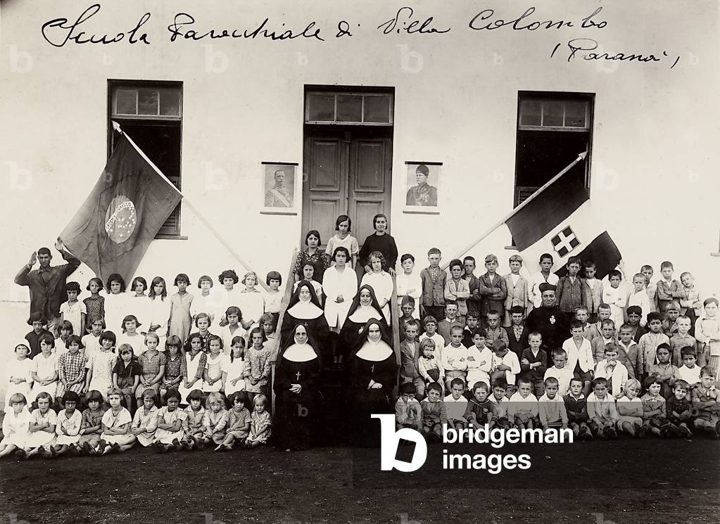 Photo of the students of the Villa Colombo Parochial School in Paranà, Brazil. Next to the door of the school, there are portraits of Mussolini and Getullio Vargas, the head of the Brazilian government (b/w photo)