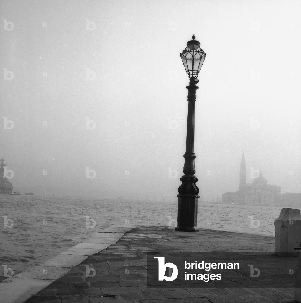 Street lamp on a pier in Venice. In the distance, the Basilica of San Giorgio Maggiore (b/w photo)