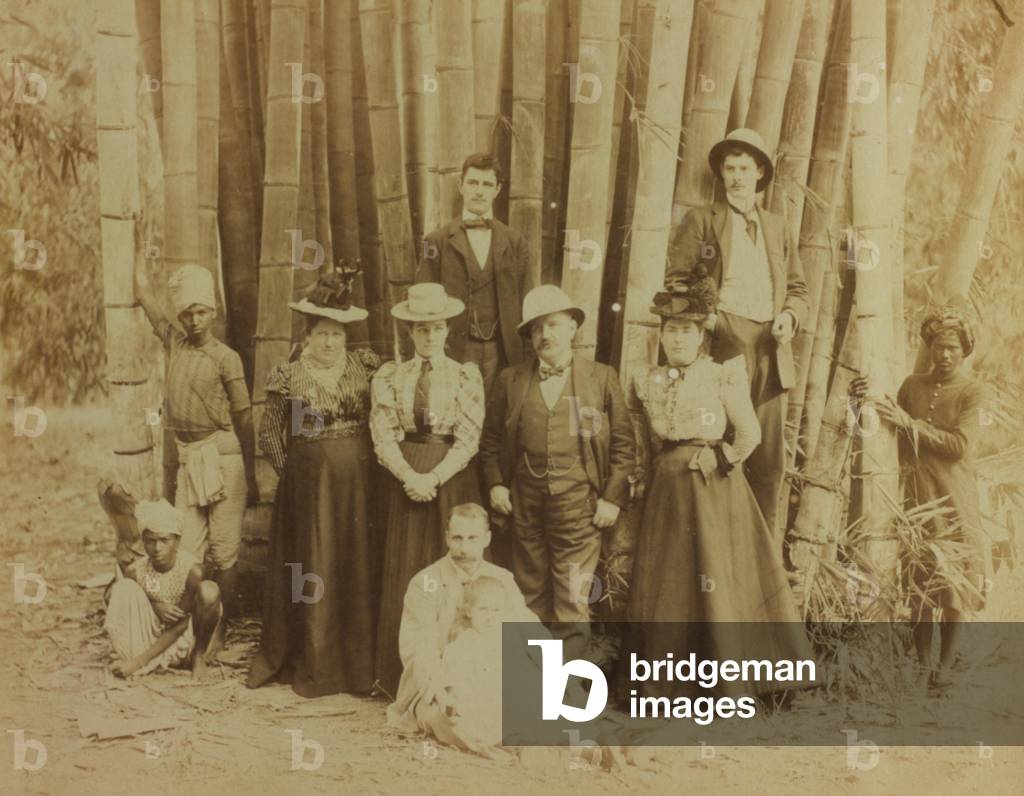 Group of Westerners shown with a few Asian natives against a background of a dense stand of bamboo canes