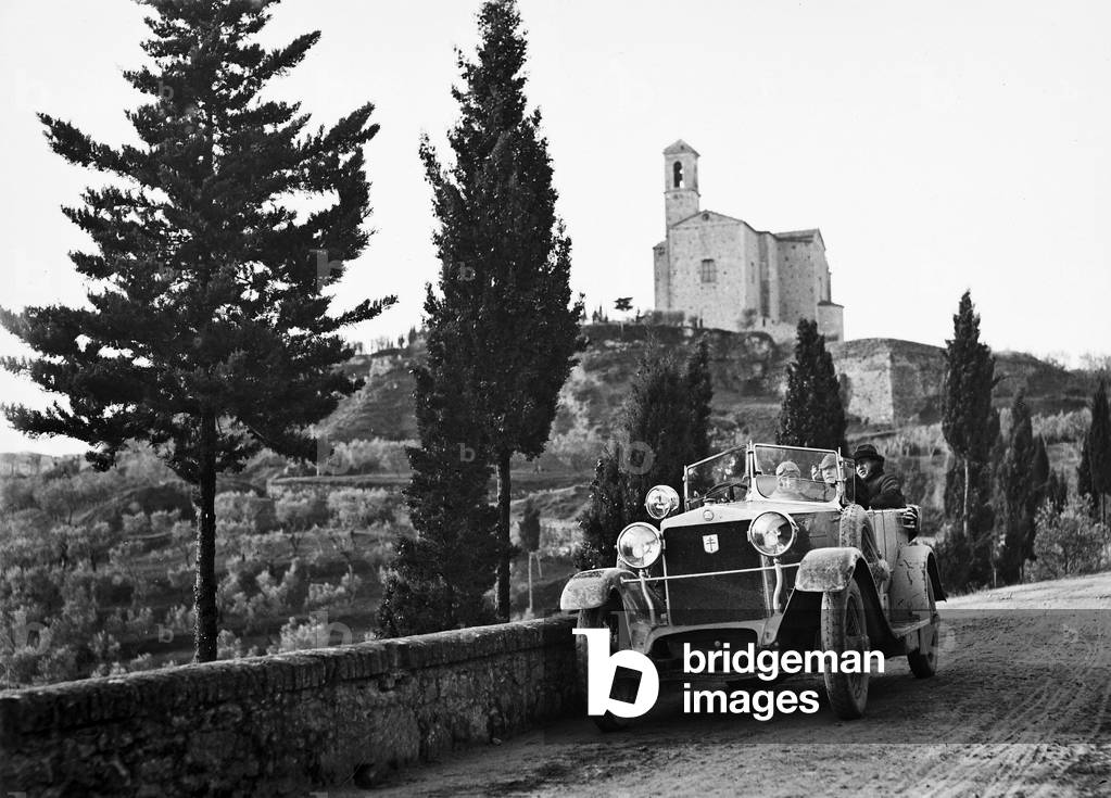 Portrait of a group in a car near Volterra. In the background the church of San Giusto and San Clemente
