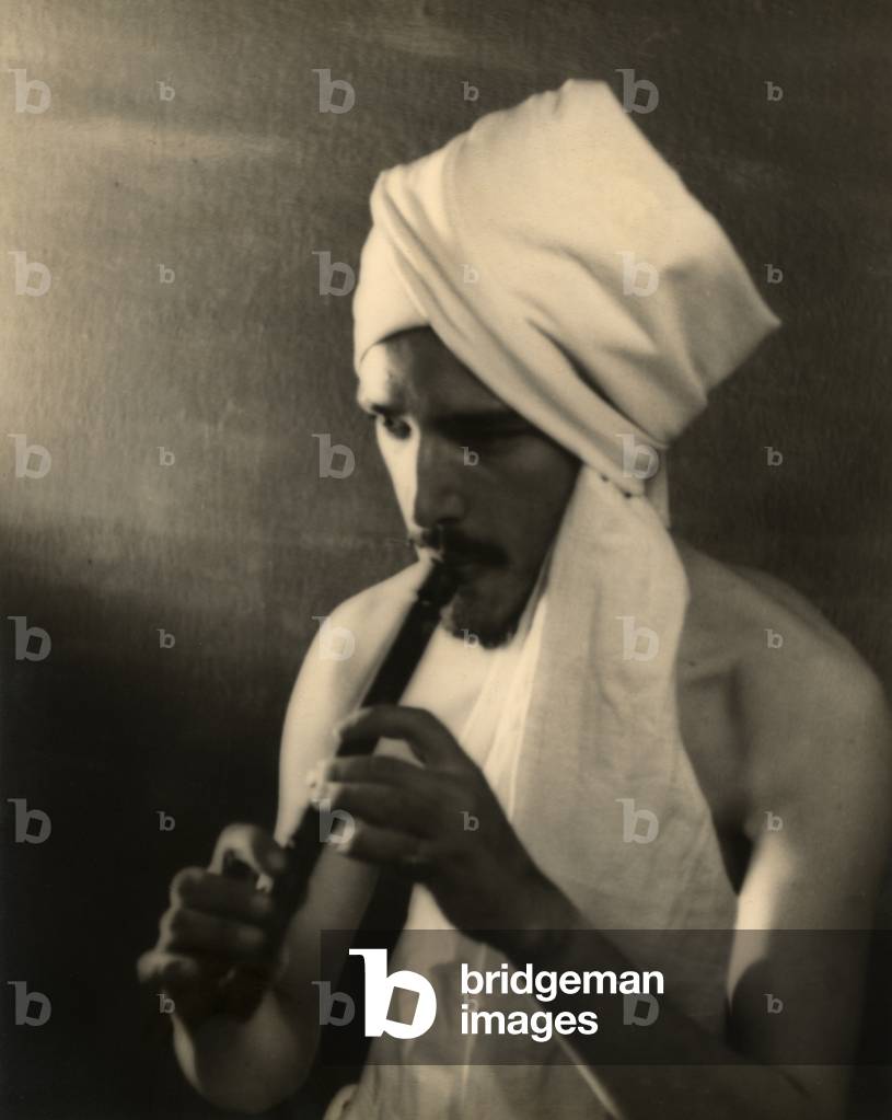 Young man with a turban playing the flute (b/w photo)