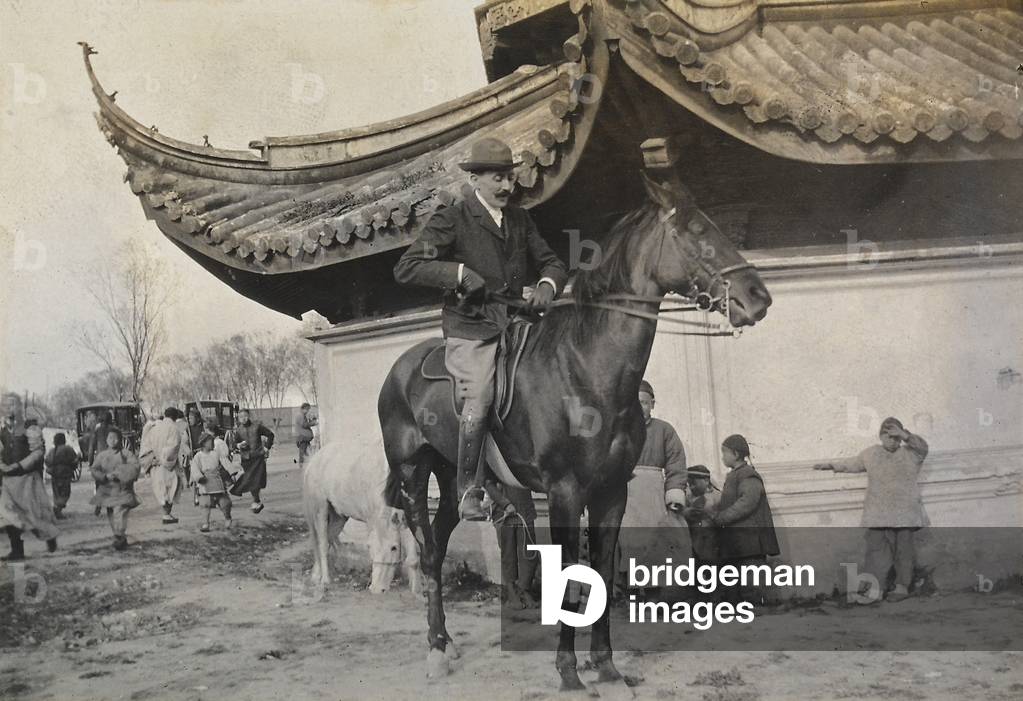 A man on horseback in a Chinese neighborhood