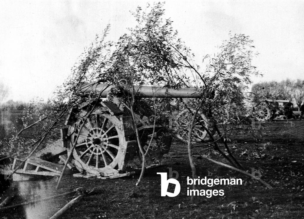 A huge French cannon, camouflaged with some leafy brunches. In the background other cannons are visible. This weapon is employed in the Battle of Ypres, fought between 22 April and 25 May 1915. (b/w photo)