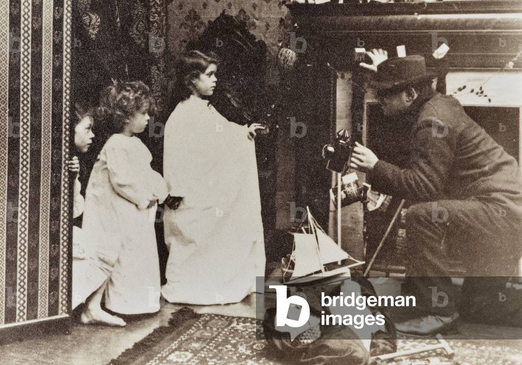 A man shows three little girls a few toys he has in a bag.