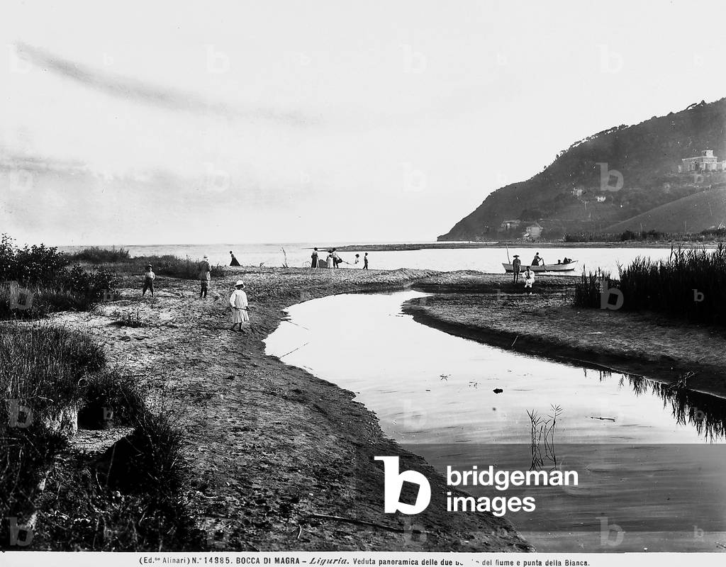 A panoramic view of the river at Bocca di Magra, in Liguria. The picture shows the mouth of the river, some people on the shore, a boat and the background Monte Marcello