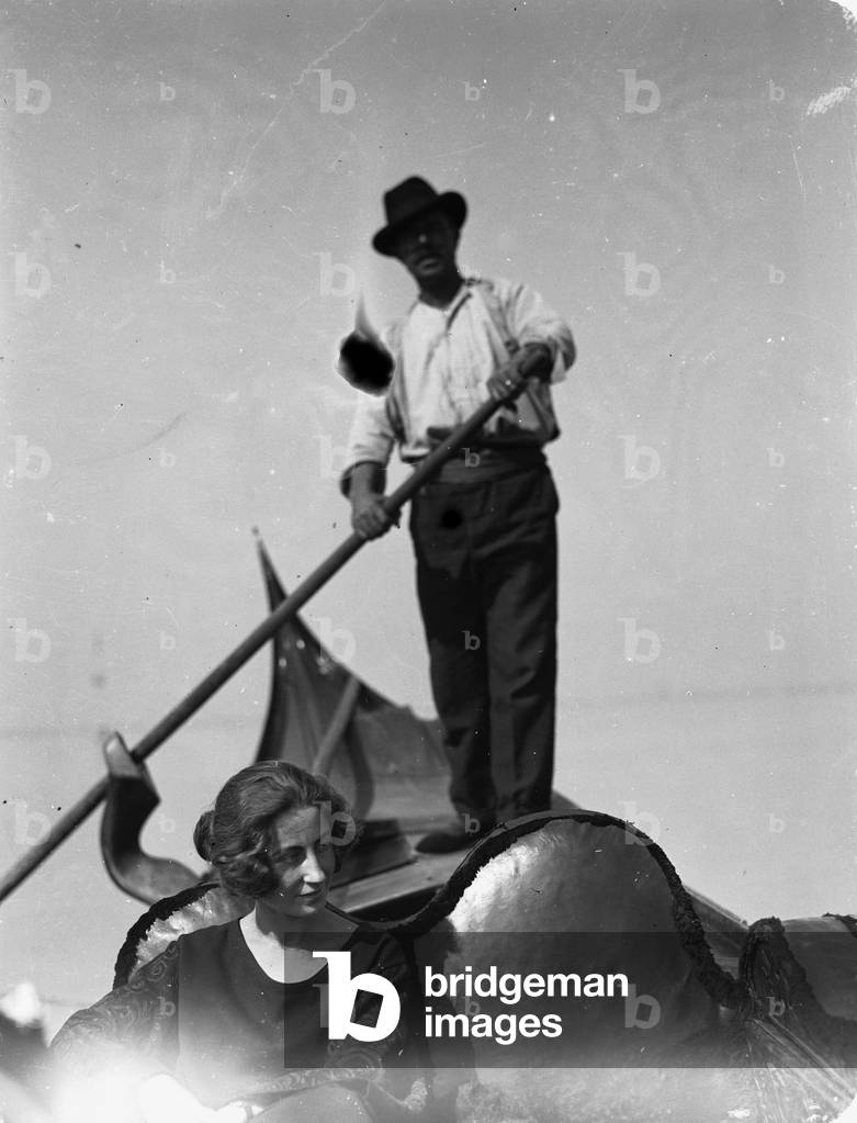 Young woman in a gondola guided by a gondolier on the canals of Venice